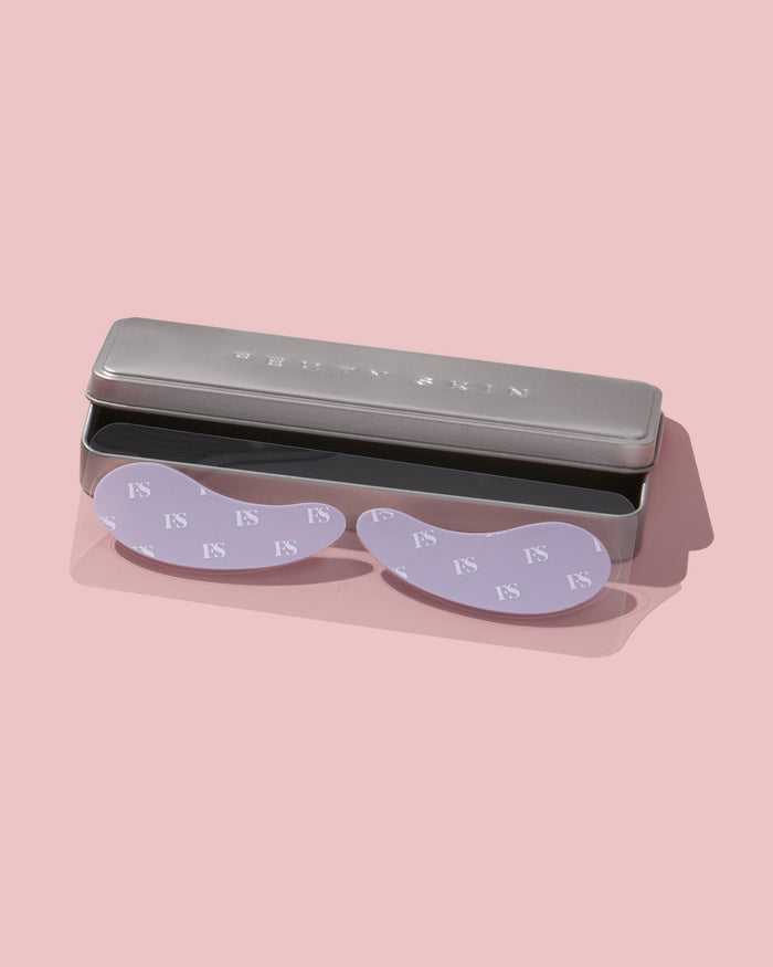 Fenty Skin under eye masks and silver container on a pink background.