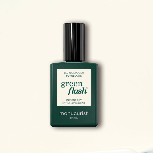 A dark green bottle of Manucurist Porcelaine Green Flash LED gel polish with a black cap stands on a light beige background.