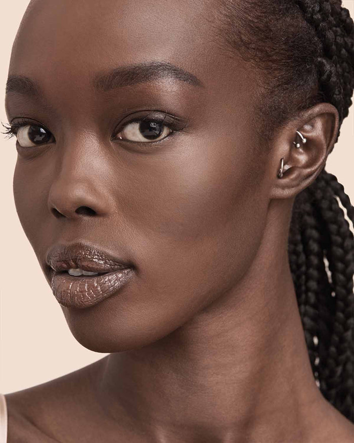model with deep skin tone wearing Fenty Beauty Pro Filt'r Soft Matte Powder Foundation