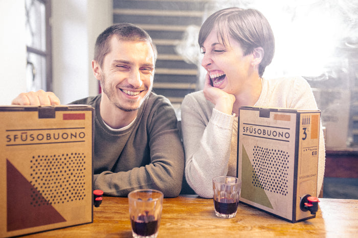 Wine tasting event: two smiling people with SFUSUBUONO wine boxes on table