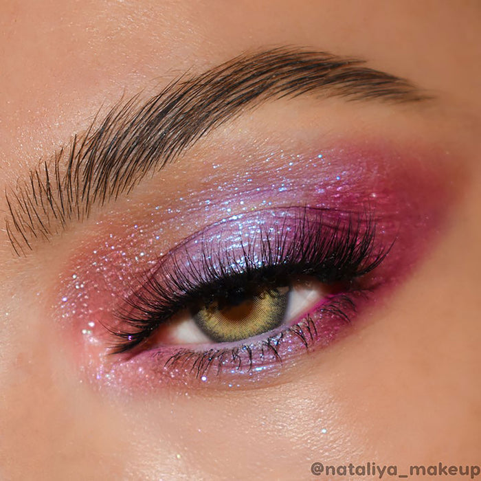 Shimmery rose-lilac eyeshadow sparkles across the eyelid, blended from pink to plum with blue microglitter and long lashes in focus; ColourPop Super Shock Shadow Pug Life shade shown in a close-up beauty look.