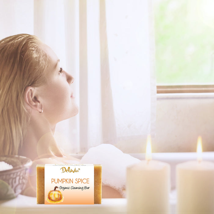 A woman in a bubble bath with candles and a bar of Deluvia soap.