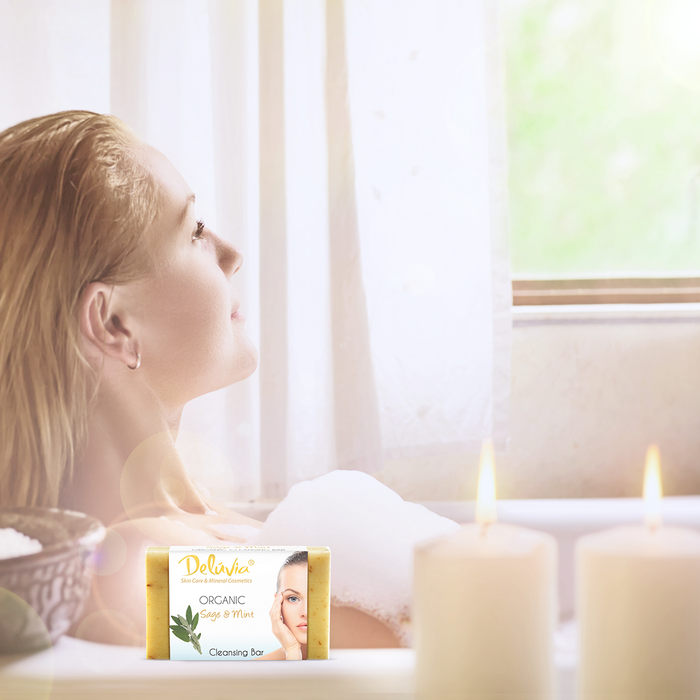 A woman in a bubble bath with candles and a bar of soap