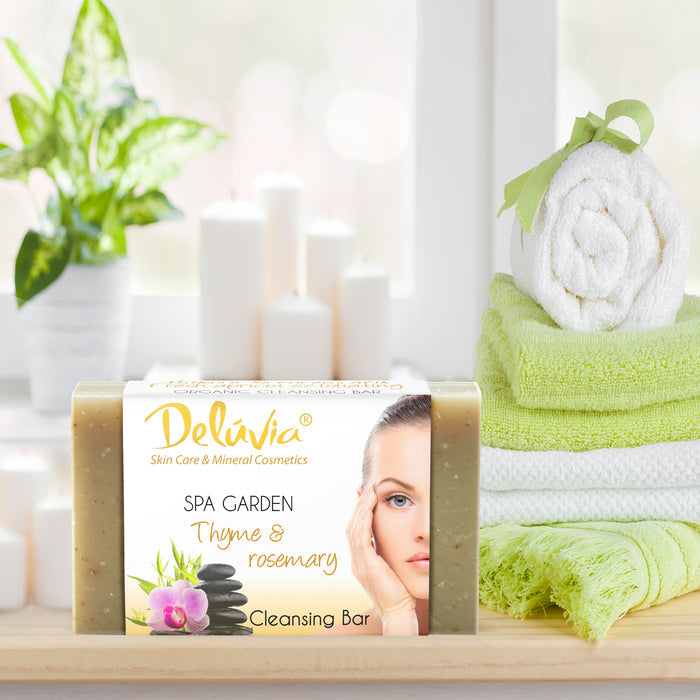 Deluvia Thyme & Rosemary Soap bar on a bathroom counter with towels and a plant.