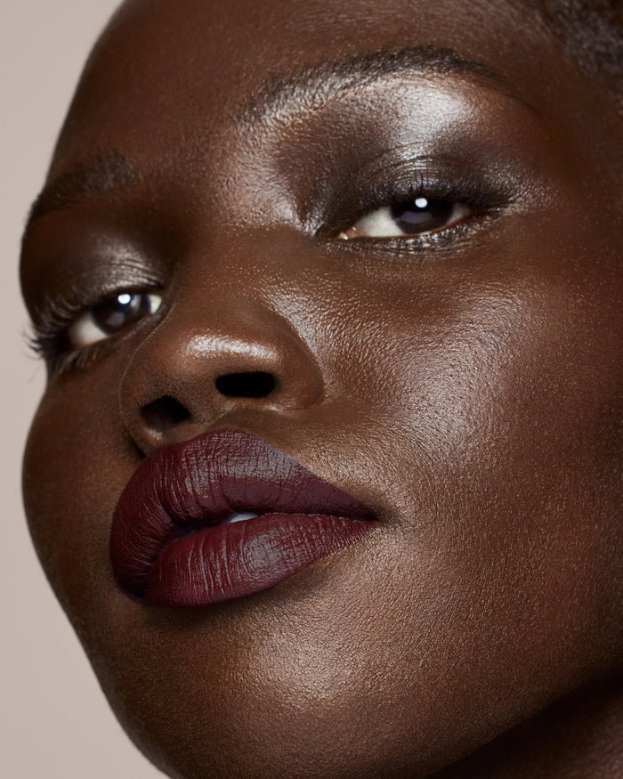 deep skin toned model wearing stunna lip paint in the shade underdawg