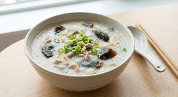 Bowl of congee with sliced pork and green onions. preserved eggs