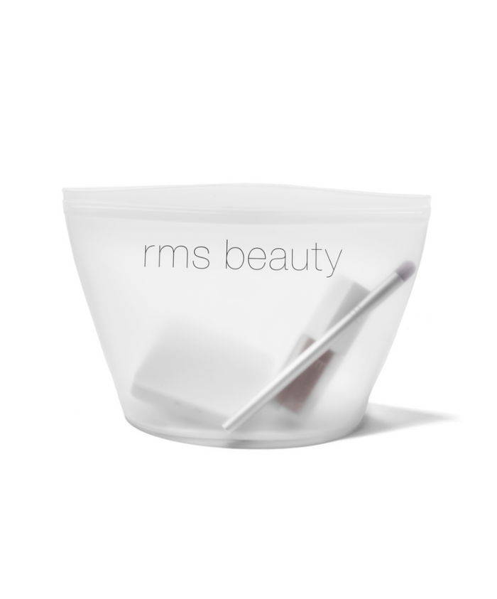 Transparent white Sustainable Makeup Bag by rms beauty, shown holding makeup tools and cosmetics, featuring clean beauty and recyclable packaging.