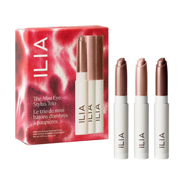 ILIA The Mini Eye Stylus Trio set, showing the red and pink patterned product box alongside three white cosmetic pencils with rose-gold capped tips on a white background.