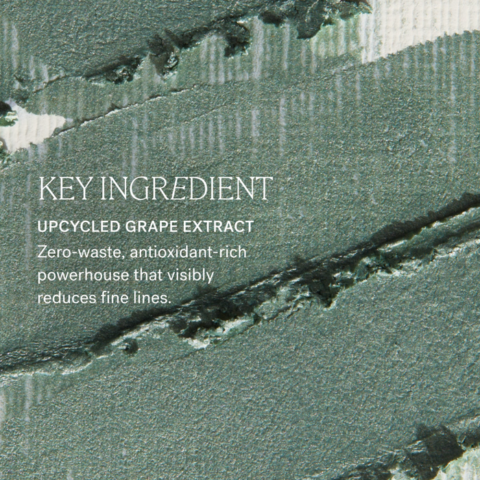 Text overlay reading 'KEY INGREDIENT UPCYCLED GRAPE EXTRACT' over a textured close-up of a muted green-gray cosmetic or skincare surface with brushstroke-like patterning.