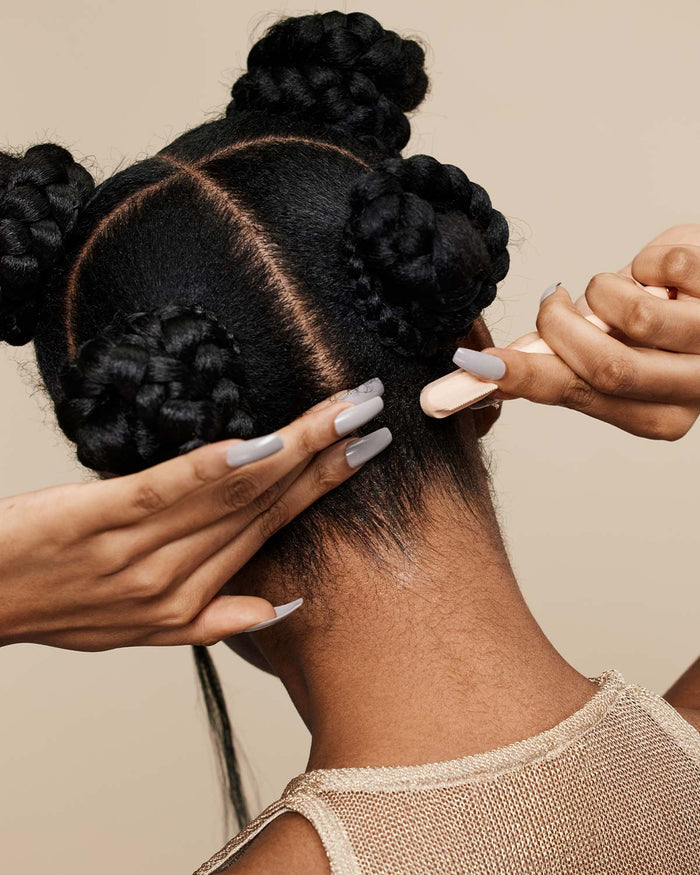 model with braided buns slicking her baby hair on the back of her neck