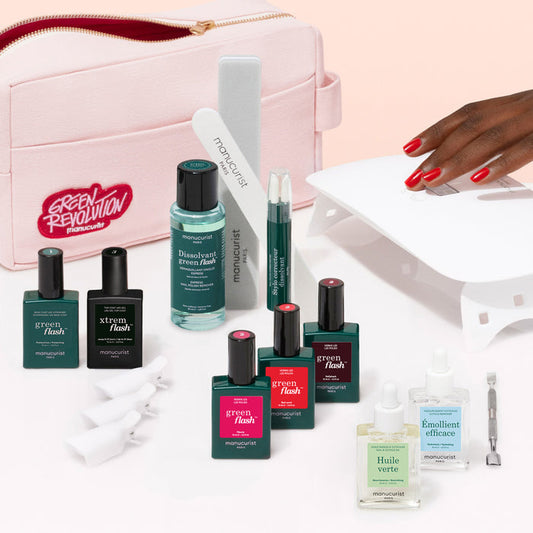The Manucurist Ultimate Kit features a pink cosmetic bag surrounded by nail care must-haves: vitamin-infused base coat, gel polish, remover, pen applicators, nail file, UV lamp, and a manicured hand with an ultra-glossy finish.