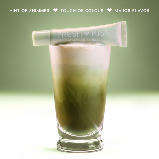 ColourPop Vanilla Matcha Fresh Kiss Glossy Balm with pearl finish rests open across a layered iced matcha latte, glossy Lip Gloss & Lip Oil texture glistening under bright studio lights against a bold pink backdrop.