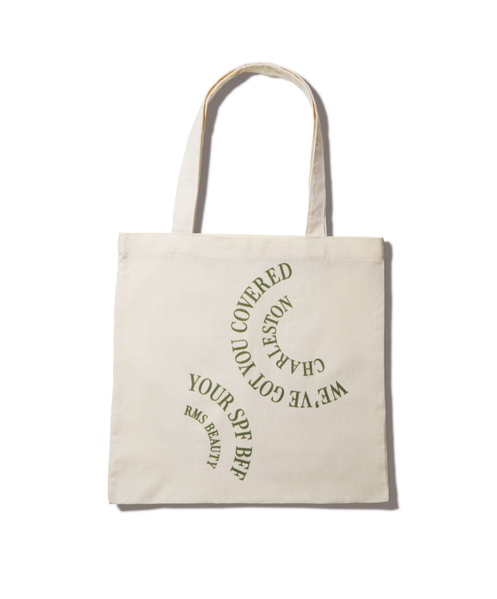We've Got You Covered Charleston Tote in natural fabric with green curved text reading "We've Got You Covered Charleston" and "Your SPF BFF RMS Beauty," eco-friendly reusable bag for clean beauty essentials.