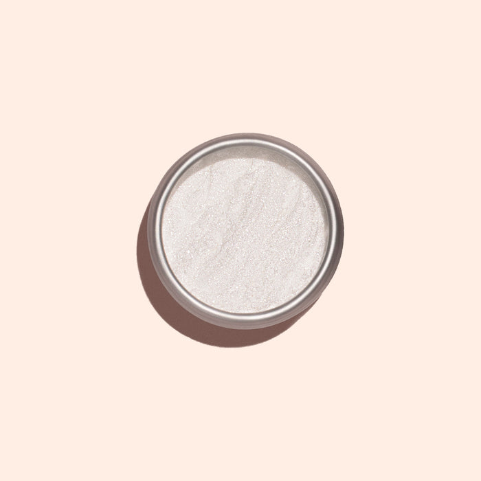 The Manucurist White Glazed Effect Powder, a fine shimmery white powder in a small round metal tin, is displayed against a pale beige background with a soft shadow to the left—ideal for creating glazed nail looks.