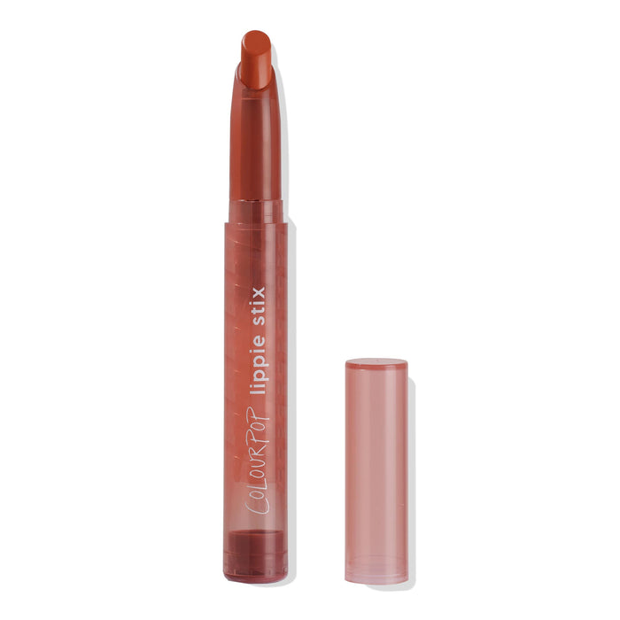 Ziggie ColourPop Lippie Stix stands uncapped, slanted brick-red tip extended, in a translucent rose tube with the cap set to the right on a white background; creamy lip crayon lipstick for everyday makeup.
